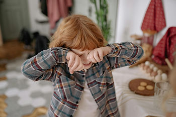 An overstimulated boy covering his eyes.
