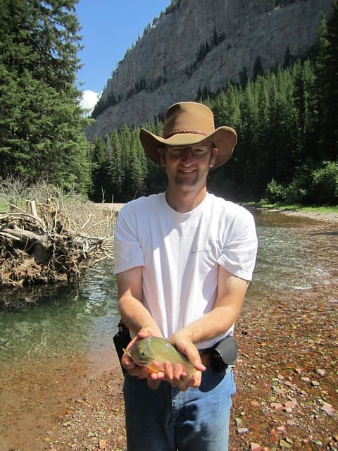 Shane Greet holding a fish in a river