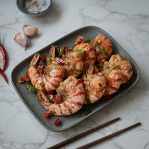 Crevettes sautées au sel et poivre servies sur un plat gris, huit crevettes croustillantes recouvertes de dés de poivron, ail et assaisonnement parfumé.