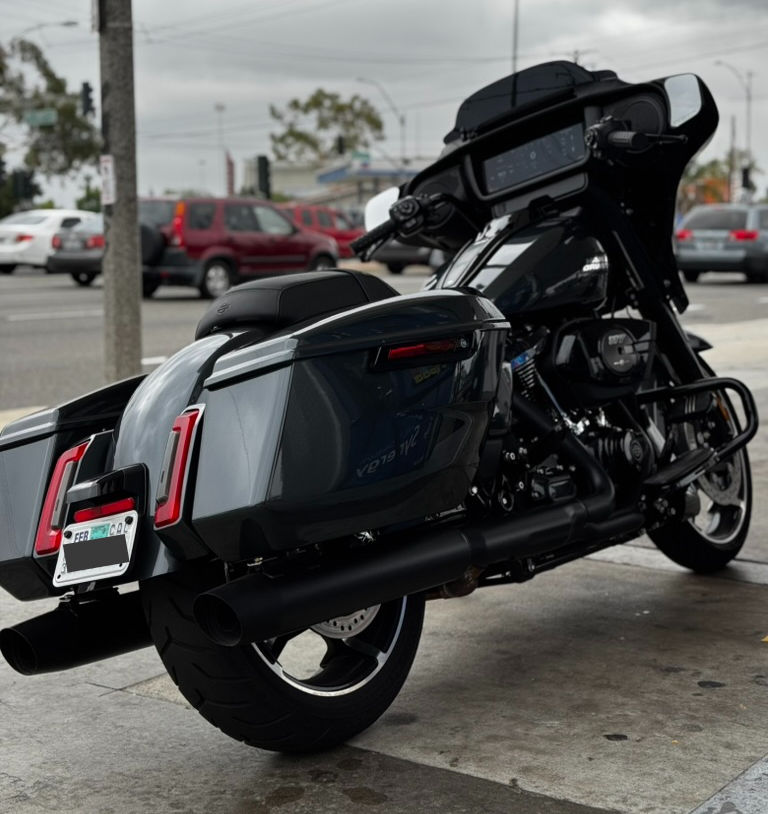 Rear-right angle at a gas stop—showcasing the contoured saddlebags, extended brake lights, and that massive infotainment screen glowing through the fairing. Iron Horse Metallic really pops under the canopy lights.