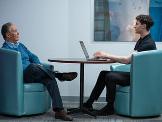 two men comfortably sitting while having a discussion at a table