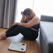 A lady disappointed at her weight after looking at the scale.