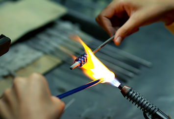 The process of blowing glass bead products. Hand made glass beads in the fire out of red h