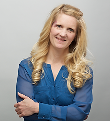 Tiffany Meyer headshot - long blonde hair smiling at camera, arms folded in front, wearing a blue blouse