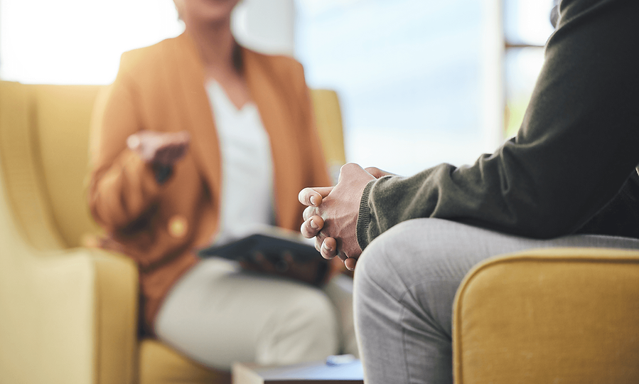 Patient sits with hands clasped while talking with a mental health provider.