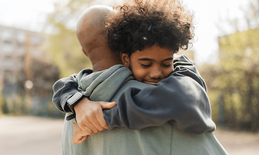 Young person embraces an adult in a supportive hug.
