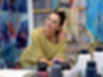 die Malerin Chantal Hediger vor blauen Acrylbildern und Ateliertisch belegt mit diversen A