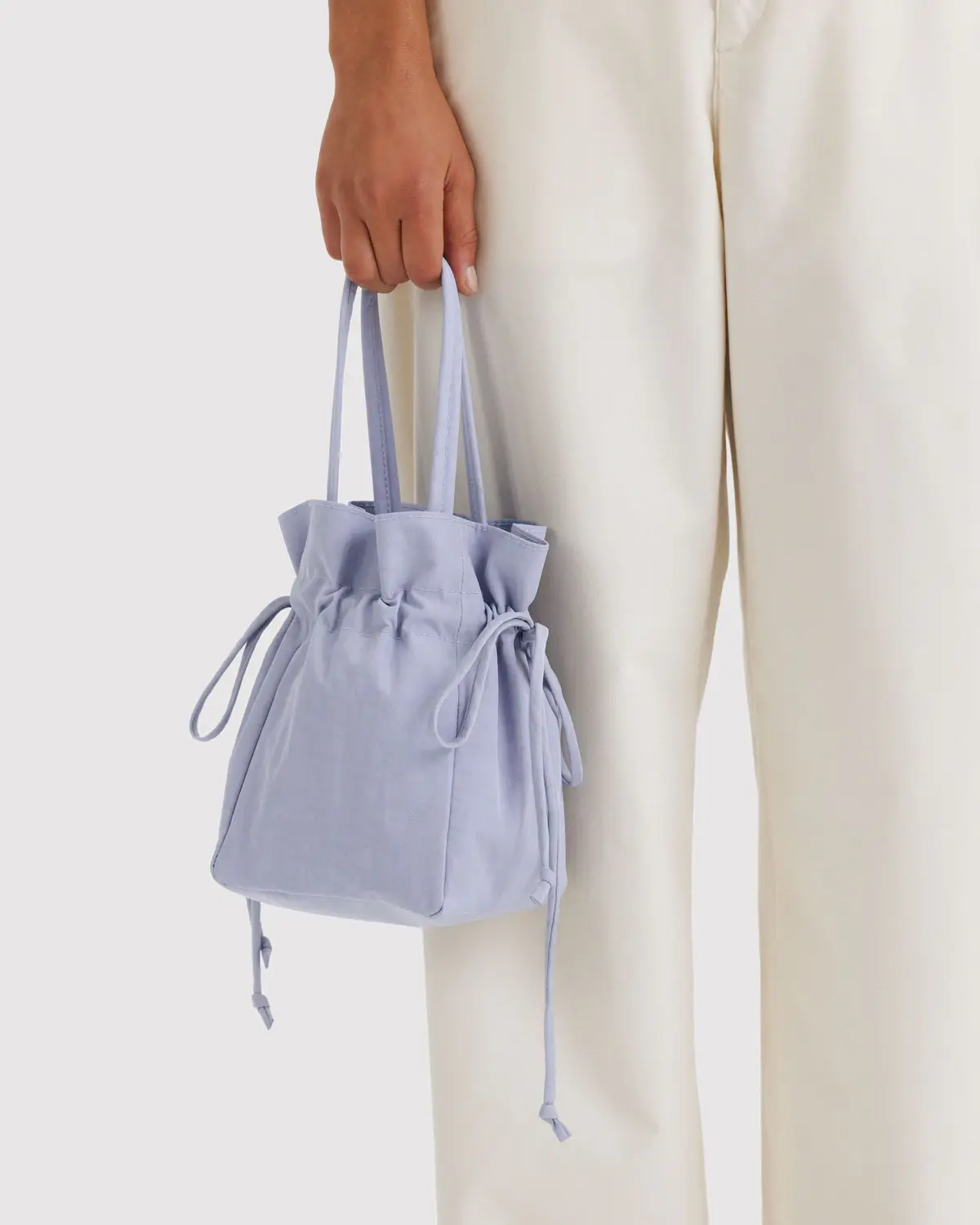 BAGGU Nylon Drawstring Bag Mist, Frau trägt sie in rechter Hand