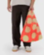 Ein Mensch hält die BAGGU Bag Standard Standard Yubari Melone in der linken Hand