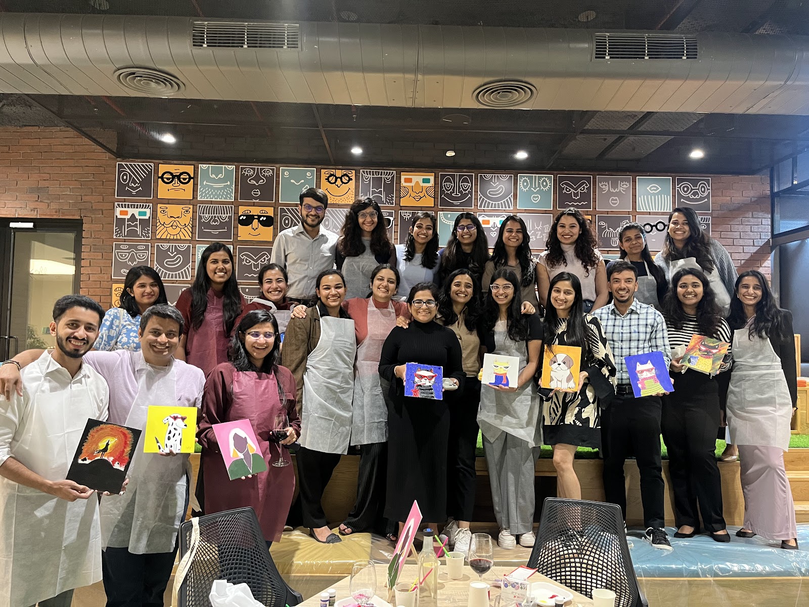 A large team holding the canvases they painted at their office