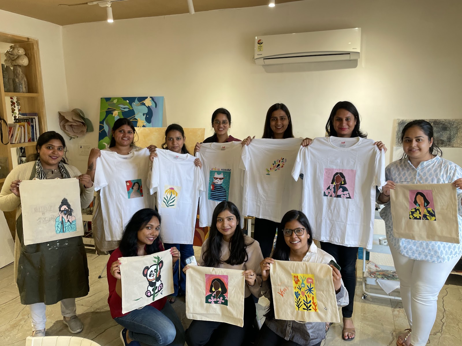 A team holding the totes and T-shirts they painted