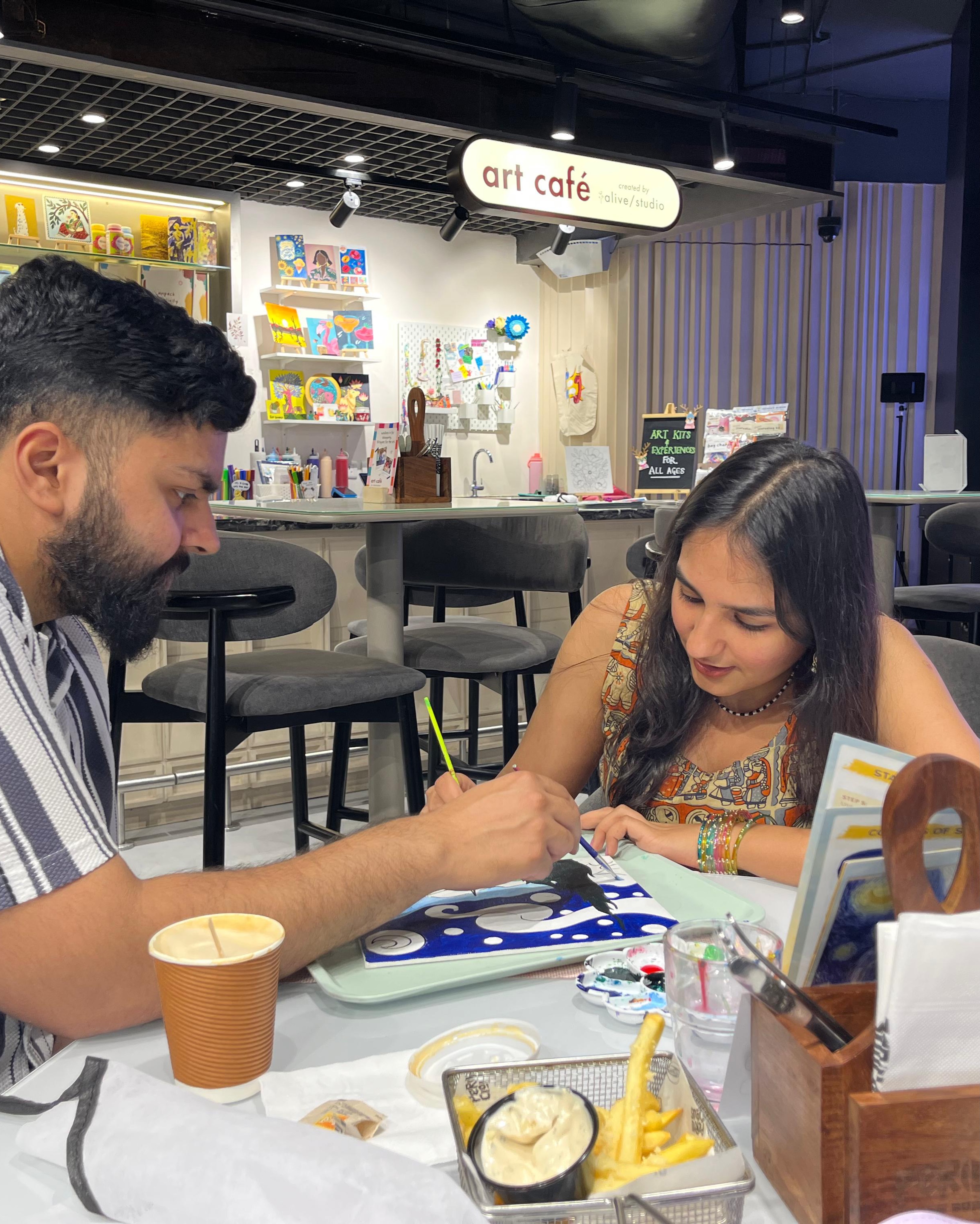 A dad helping his daughter paint at Delhi Art Cafe