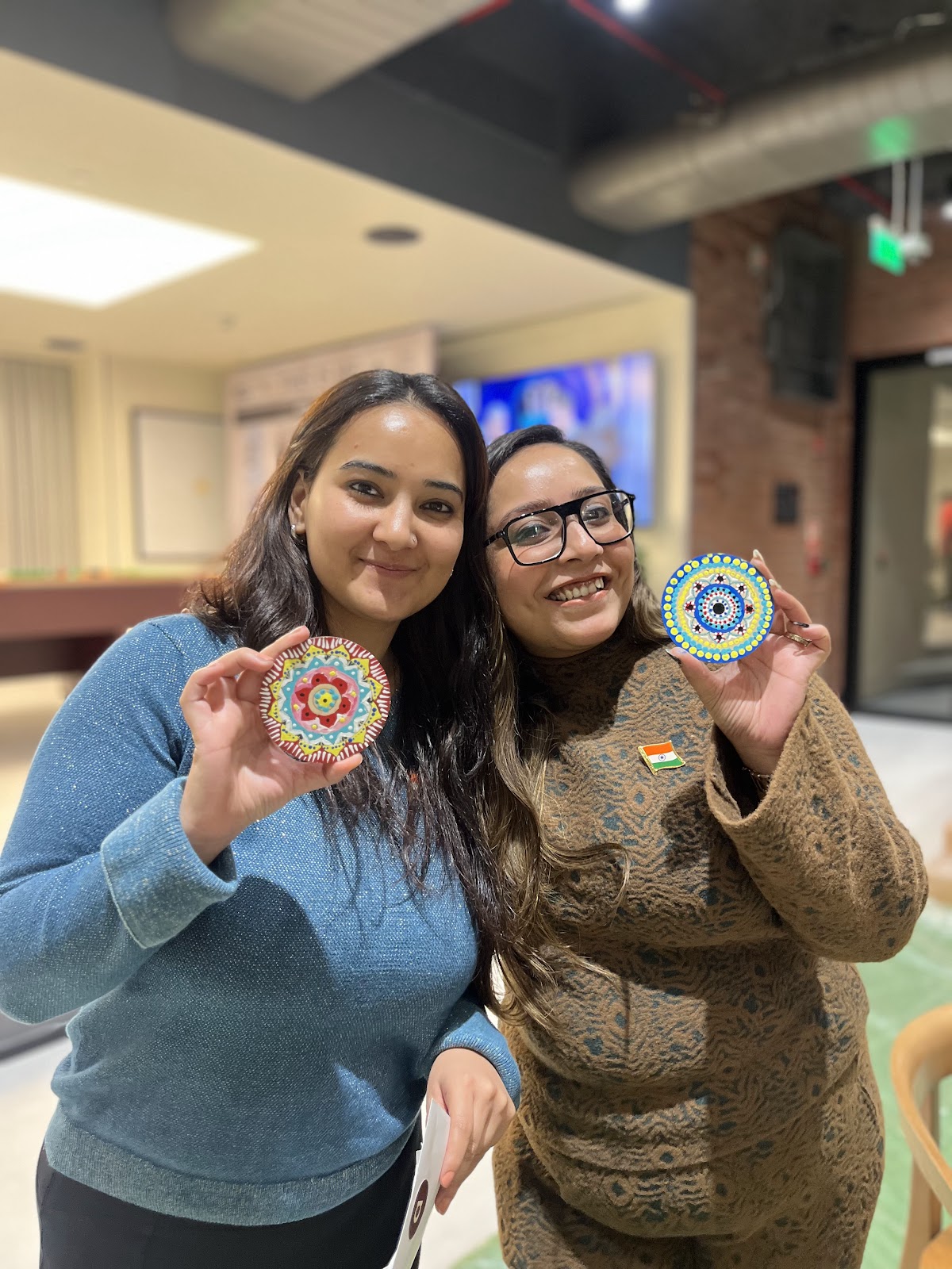 Two colleagues holding the coasters they painted