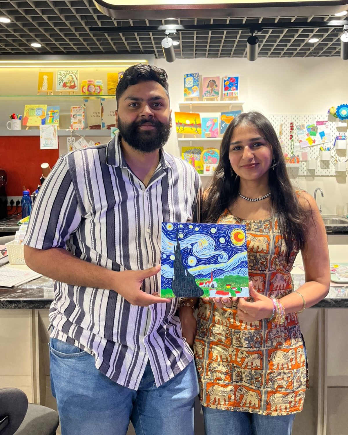 Couple with finished landscape canvases at Delhi Art Cafe