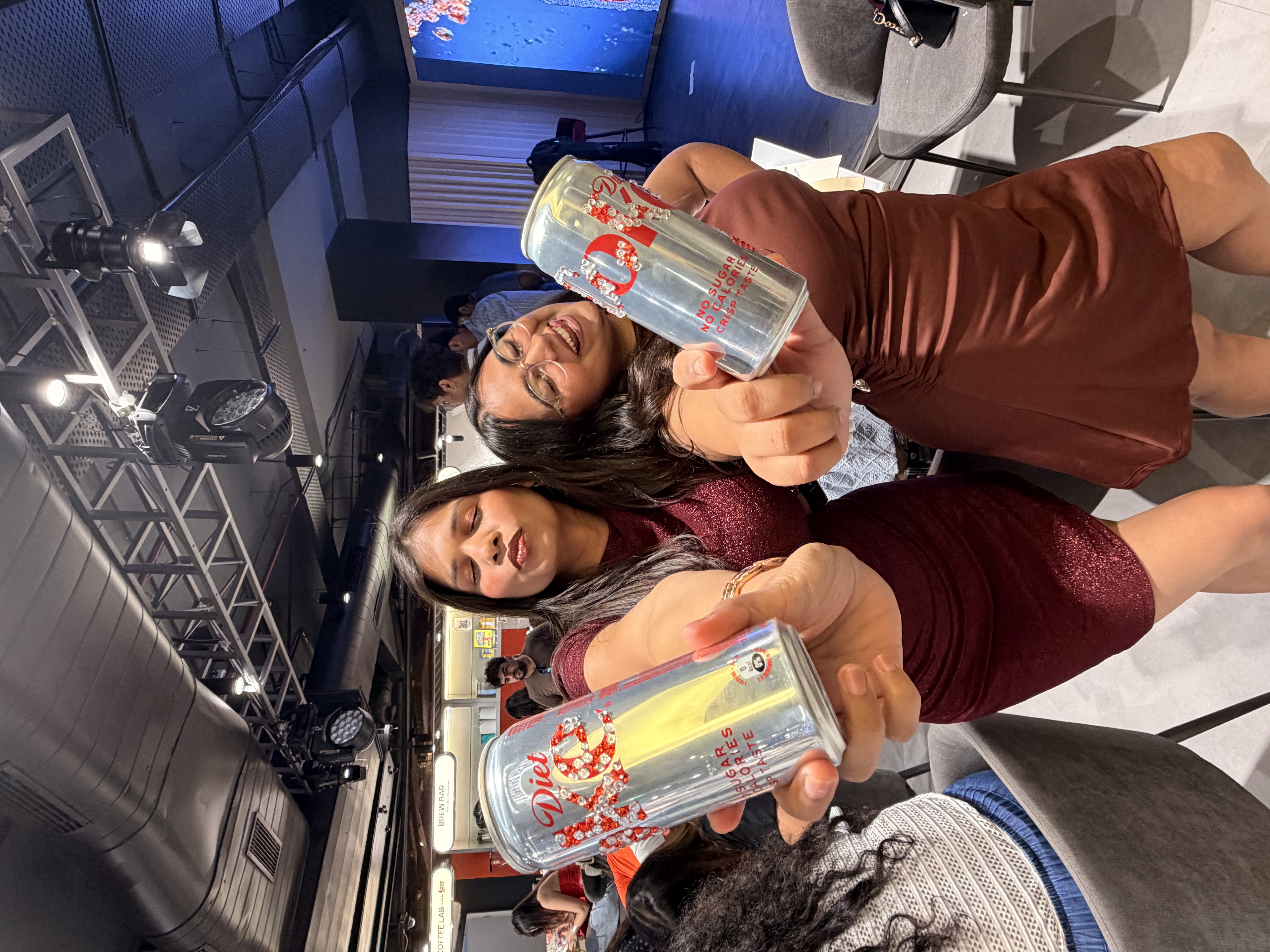 Friends posing with Diet Coke cans at the Delhi Art Cafe