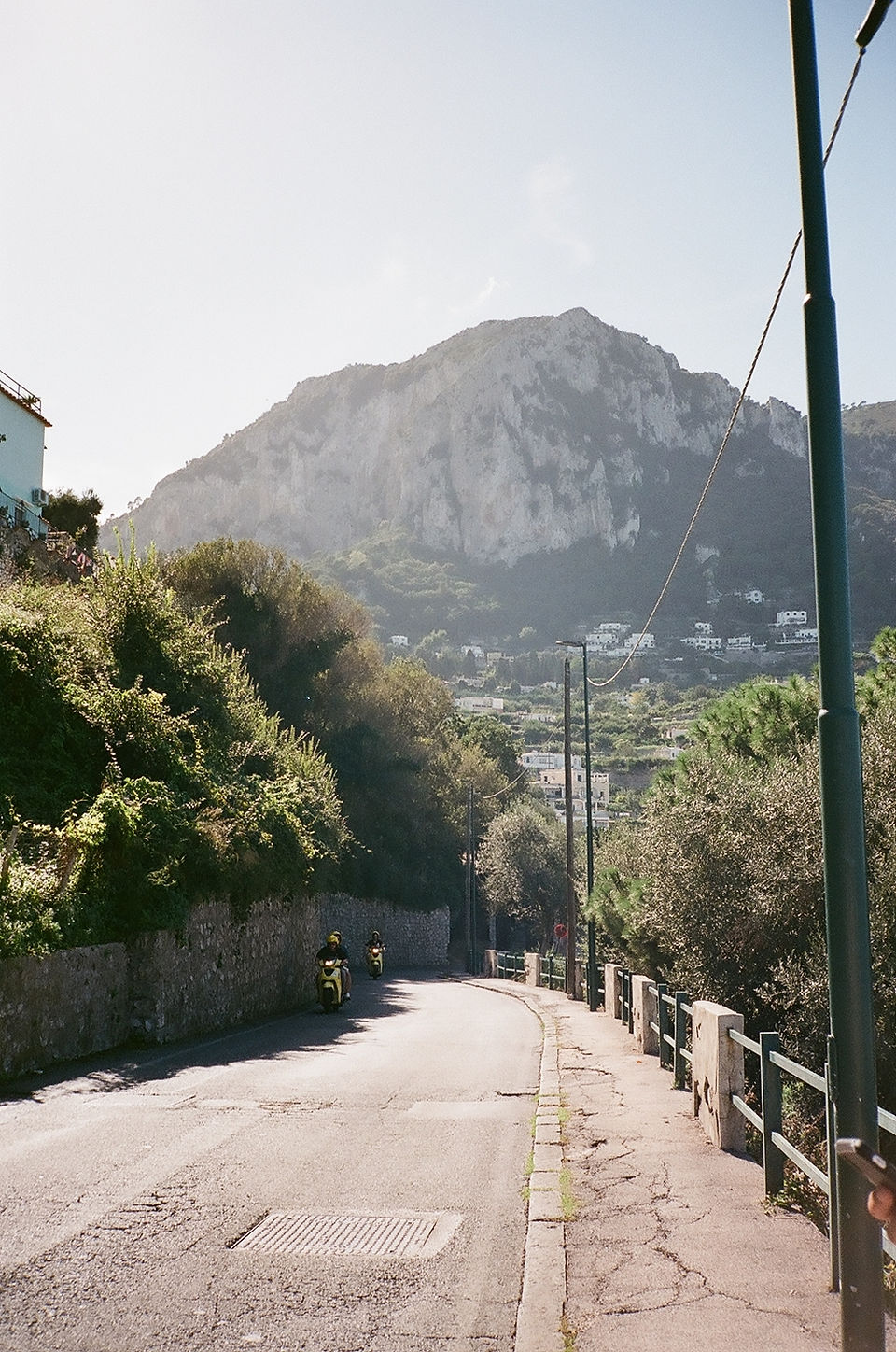 motorcyclists on the road in capri italy, mountain in the distance, shot on film