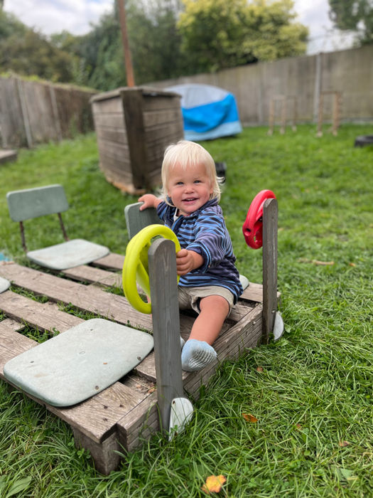 A smiling toddler on a garden play frame