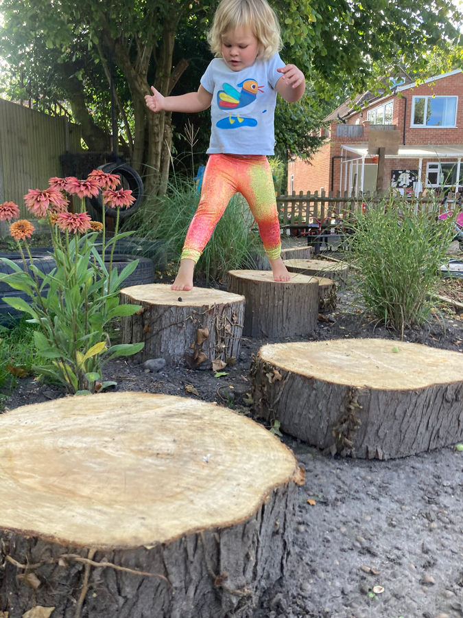 A child stepping across log stumps in the garden