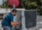An HVAC technician performing maintenance on a rooftop HVAC unit
