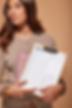 Woman holding a clipboard with a daily planner checklist used for ADHD task organization and time management.