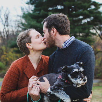 White couple kissing. holding dog. fall