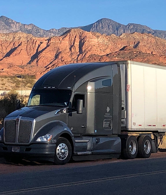 Interwest Transportation semi-truck hauling freight through southern Utah desert landscape at sunrise, showcasing dedicated trucking and 3PL hauling services.
