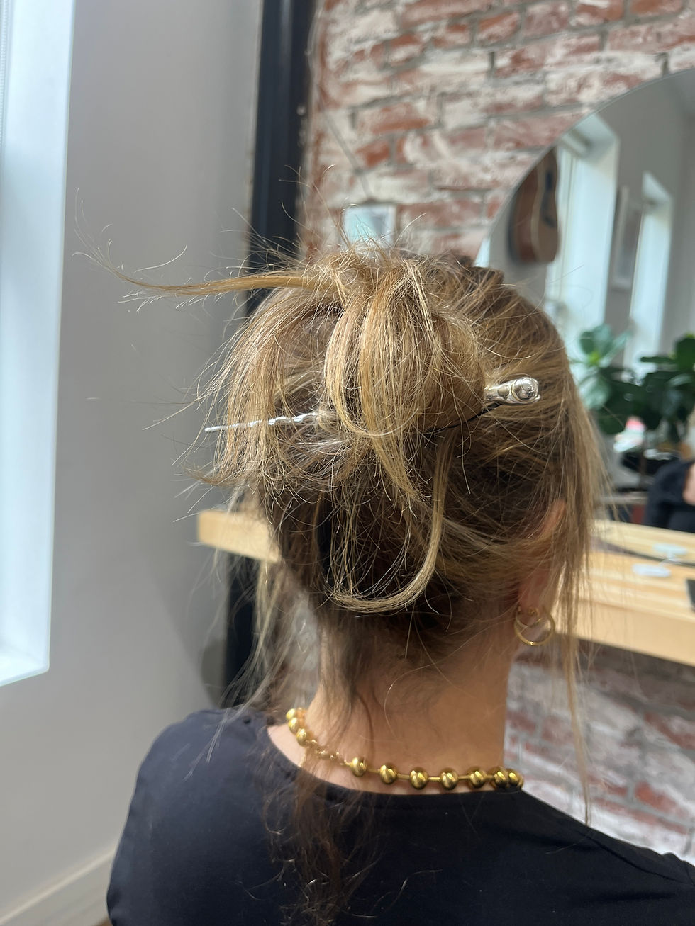 Close-up view of a gold water-resistant hair pin holding a smooth hairstyle
