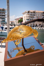 Sculpture de tortue dorée en fil de fer au bord du canal.