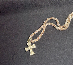 Close-up of a finished gold Hilandarski Krst Serbian Orthodox cross pendant on a chain.