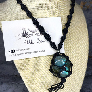 Black rope style necklace holding a blue, irredescent crystal stone. Hidden Gem is a LGBTQ+ Favours & gifts wedding supplier, part of the Rebel Love Directory.