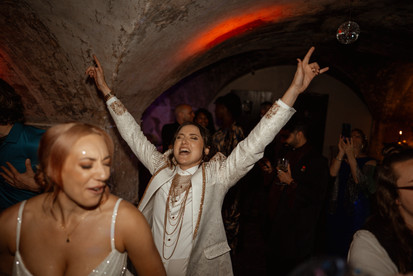 Brooke and Lilly dancing joyfully with guests during their LGBTQ+ wedding reception at The Mount Without in Bristol. A vibrant celebration filled with laughter, sparkles, and chosen family, captured by Rebel Love Club, queer wedding photographers in the UK.