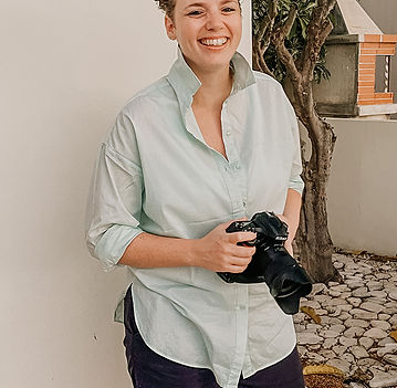 A joyful bridal party with colored smoke bombs creating a whimsical backdrop, all wearing matching dresses, with the brides in the center