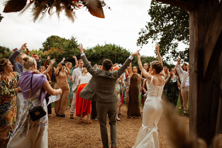 LGBTQ+ couple celebrate with their friends and family at the end of their wedding ceremony at The Red Barn in Norfolk, by Rebel Love Club - LGBTQ+ wedding photographer UK