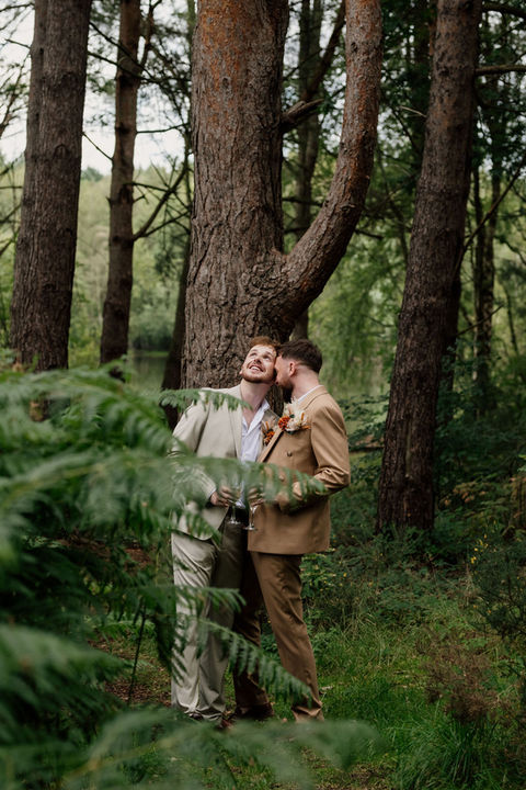 A gay wedding couple standing close together in a forest captured by LGBTQ+ inclusive wedding photographer Laura Bareham Photography