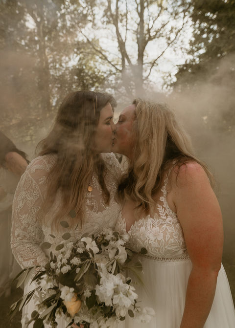 Two brides kissing in a forest in a photo by Dan Chapman Photo