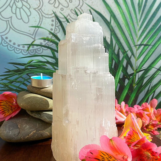 Large white crystal stood in front of green leaves, stones and pink flowers in front. Hidden Gem is a LGBTQ+ Favours & gifts wedding supplier, part of the Rebel Love Directory.