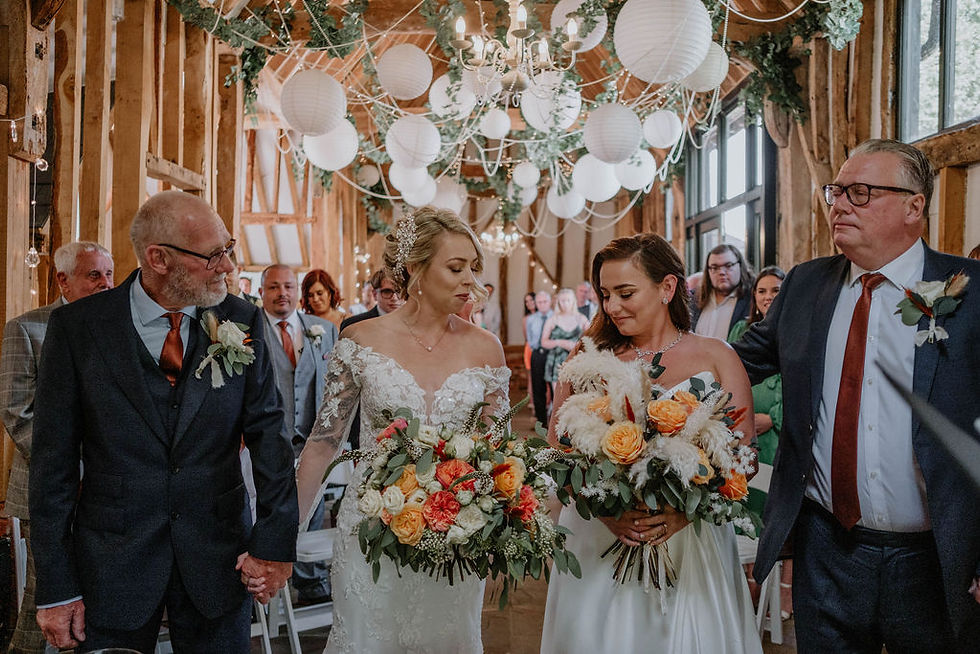 Two Brides walking down the aisle after getting married holding gorgeous wedding bouquets from Freckles and Flowers