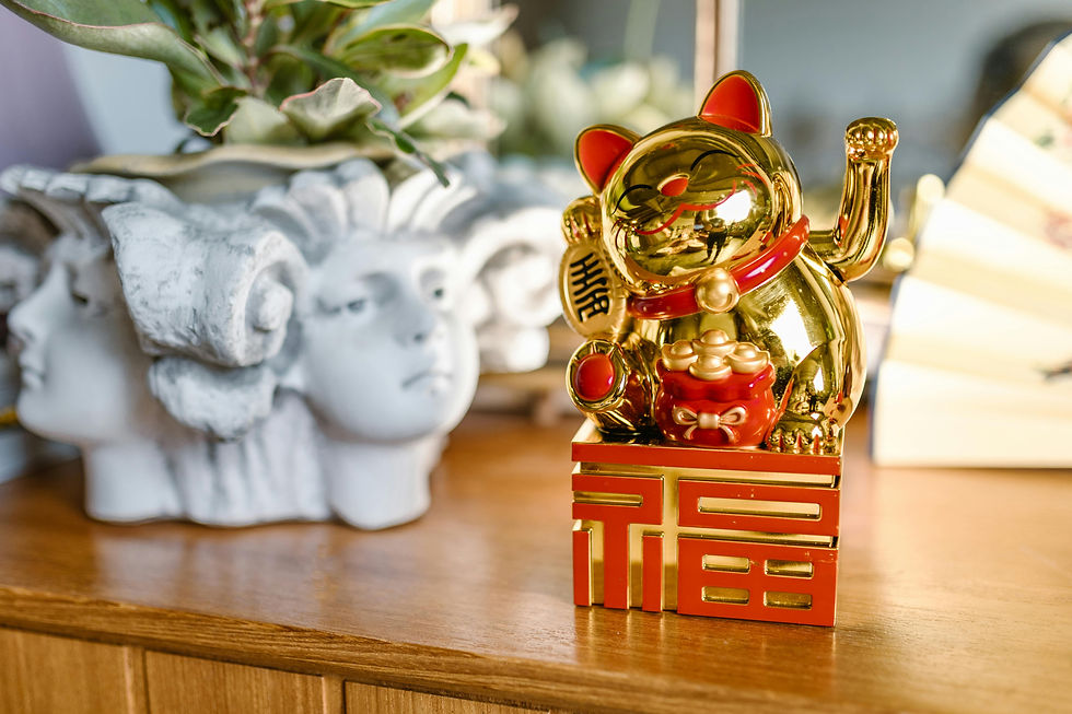 Gold lucky cat sitting on a table next to a planter