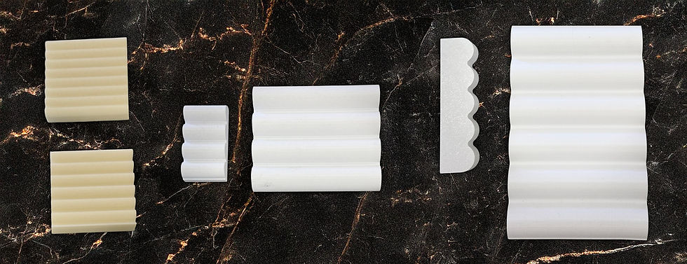 An array of 3D-printed reeded stone profile samples showing variations in groove size, depth, and spacing on a marble surface.