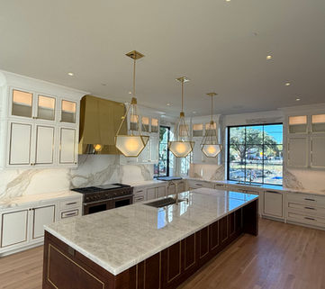 Modern kitchen with white cabinets, island, gold accents and large windows.