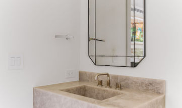 Modern bathroom with rectangular mirror, stone sink, and faucet fixtures.