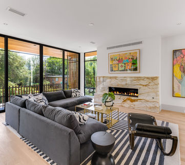 Modern living room with fireplace, art, large windows, and designer furniture.