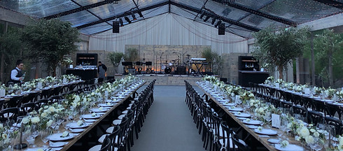 Luxury wedding reception with floral tables and AV stage setup, showing custom AV solutions for private events