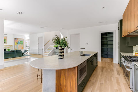 Modern kitchen with island, sink, and microwave; light wood floors and cabinets.