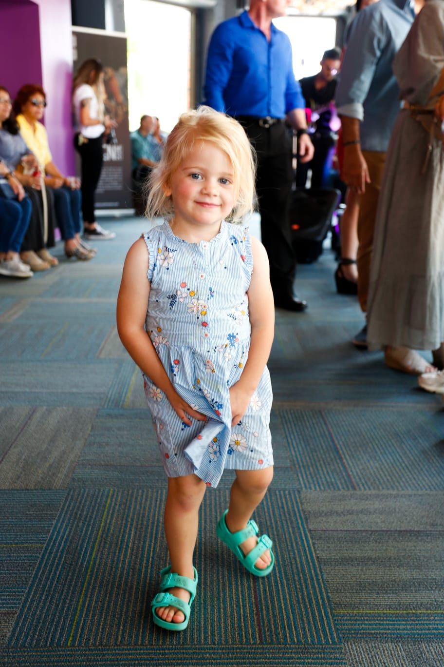 a little girl wearing a blue dress with daisies on it