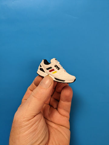 Seitenansicht eines 3D-gedruckten Miniaturschuhs, der in einer Hand gehalten wird, zeigt die Präzision und das handliche Format der für die Spendenaktion produzierten Miniaturmodelle.
