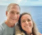 Smiling couple poses for selfie with ocean background, enjoying vacation together