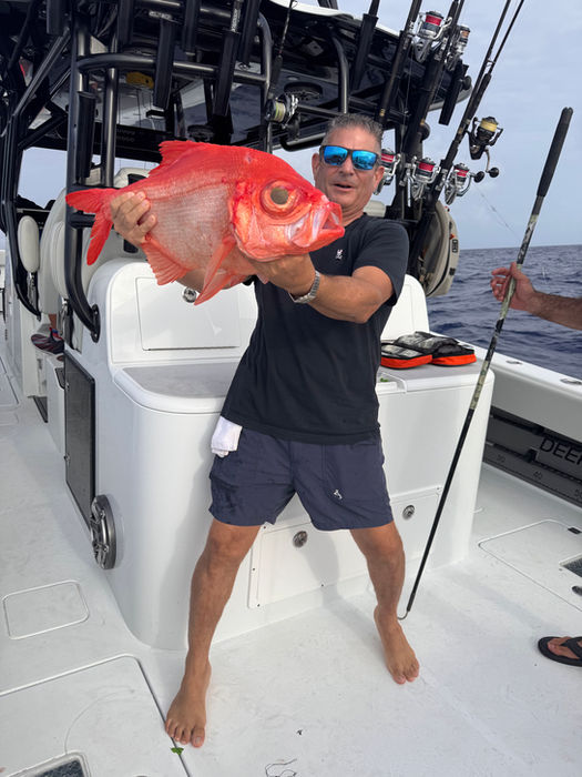Happy man holding a large red fish on a boat