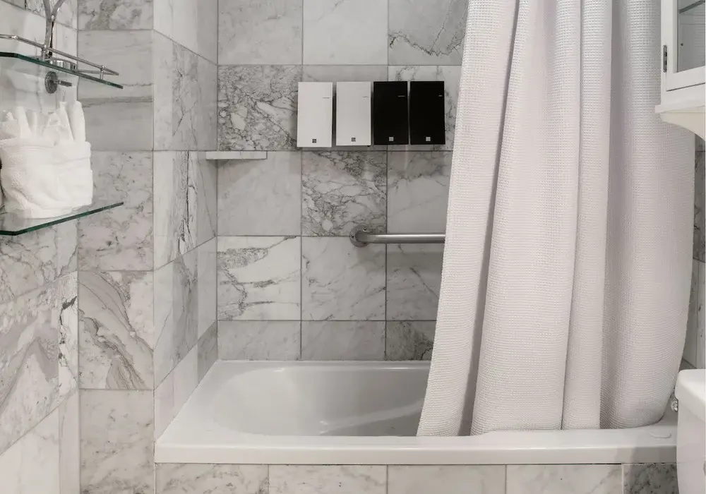 Modern marble guest room bathroom with tub and shower curtain.