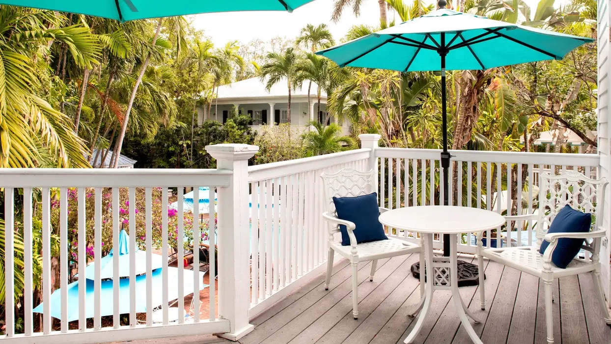 Private master suite balcony with table and teal umbrella.